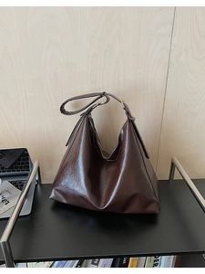 Gros plan du sac Hobo marron foncé avec texture cuir brillant sur une étagère