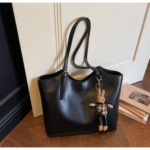 Close-up of black tote bag with textured finish, slim straps and a cute rabbit charm