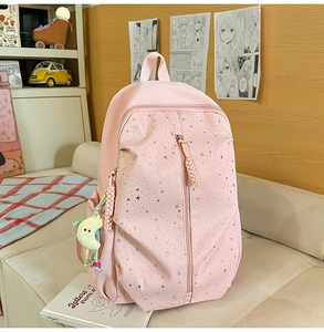 Detail of pink starry school backpack featuring double zippers and a crescent moon plush charm