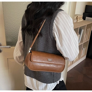 Brown retro baguette underarm bag with silver metal logo buckle shown on shoulder
