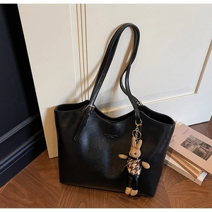 Detail of black tote bag featuring fine leather texture and a cute rabbit charm