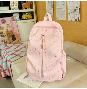 Pink backpack with silver stars on a cozy beige sofa in a warm bedroom setting