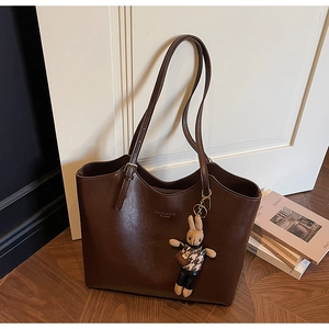 Detail of dark brown tote bag featuring adjustable straps and a plush bunny charm