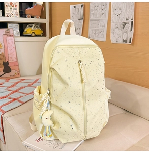 Detail of cream yellow backpack with silver stars and plush moon pendant in a cozy room