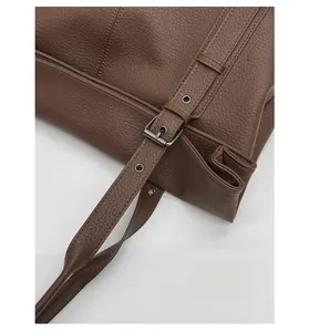 Detail of dark brown lychee leather strap with adjustable dark grey metal buckle and eyelets