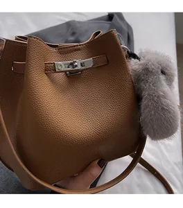 Detail of brown litchi pattern leather bucket bag with metal buckle and plush charm