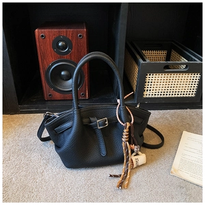 Detail of black bucket bag with lychee pattern leather and coffee cup charm