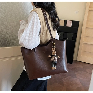 Detail of vintage brown tote bag with leather texture and cute rabbit charm ornament