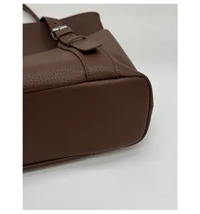 Detail of reinforced bottom base and litchi grain texture on coffee leather tote bag