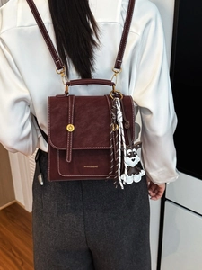 Retro burgundy leather backpack with contrast stitching and charms shown on a model