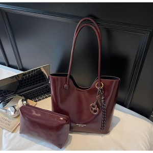 Burgundy patent leather tote bag set with small pouch on white bedding lifestyle background