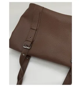 Close-up of brown litchi pattern leather tote bag with silver buckle strap detail