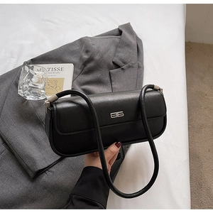 Close-up of matte black leather baguette bag with silver logo and rounded handle