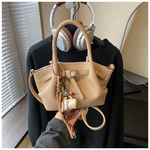Detailed close-up of khaki bucket bag with lychee grain leather and coffee cup charm