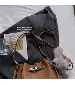 Detail of brown litchi pattern bucket bag with silver twist lock and plush charm