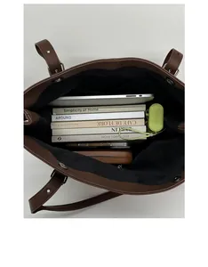 Spacious interior of dark brown leather tote bag with laptop and books for commuting