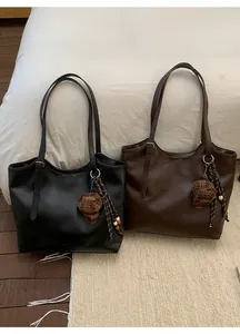 Close-up of black and brown leather tote bags with stylish charms and winter aesthetic