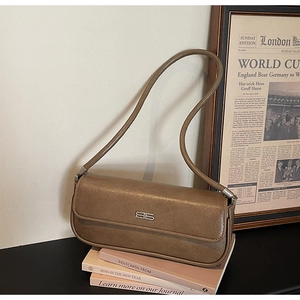 Detail view of coffee brown faux leather baguette bag with silver metal logo on books