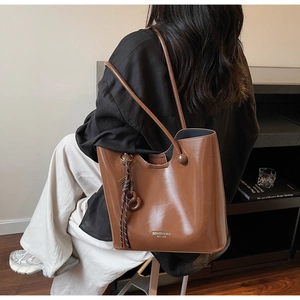 Caramel brown leather tote bag with elegant side tassel and brand logo in a lifestyle scene