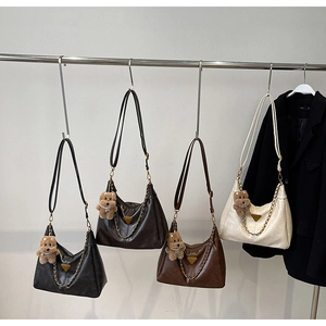 Detail view of four textured leather crescent bags in various colors with metal triangle logo