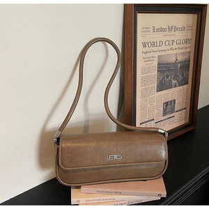 Close-up of vintage brown leather bag with metallic logo and elegant shoulder strap