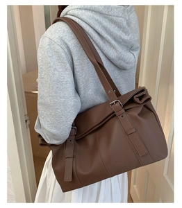 Detail of large brown tote bag showing textured PU leather and adjustable metal buckles