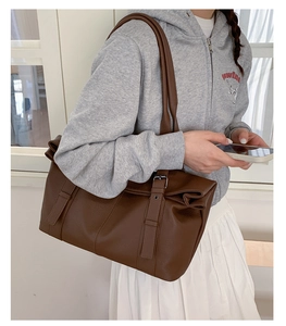 Close-up of deep brown tote bag featuring litchi grain texture and metal buckle detail