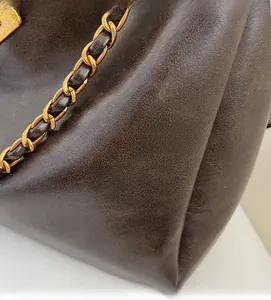 Close-up of deep brown pebbled leather texture and gold chain strap detail on tote bag