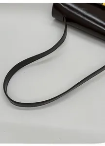 Detail of glossy leather tote bag with metallic gold buckle and premium shoulder strap