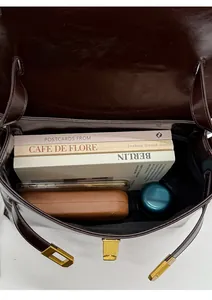 Top view of large brown vintage briefcase showing spacious interior with books and gadgets