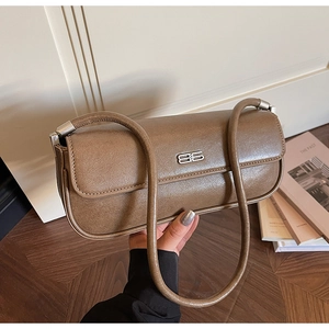 Detail of vintage brown baguette bag featuring a silver metal logo and slim leather straps