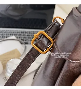 Close-up of vintage hardware buckle and adjustable leather strap on brown shoulder bag