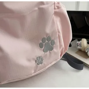 Détail du tissu rose clair avec des empreintes de pattes brodées en argent sur le sac à dos