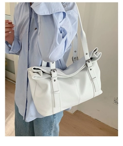 Detailed macro view of white textured leather tote bag with stylish side buckle design