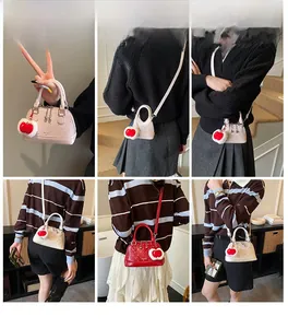 Mini-Umhängetasche in Muschelform mit Glanzeffekt und Herzanhänger am Model gezeigt