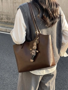 Minimalist dark brown tote bag with rabbit charm and gold accents on a model