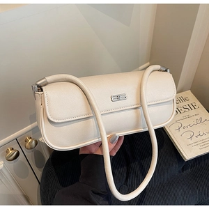 Close-up of creamy white leather baguette bag with silver metal logo and dual shoulder straps