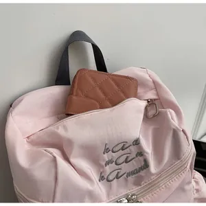 Vue détaillée du sac à dos en nylon rose avec poche frontale zippée pour portefeuille