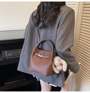 Détail d'un sac seau en cuir marron avec fermoir métallique et breloque lapin blanc