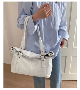 Detailed view of large white leather tote bag with vintage metal rings on shoulder straps