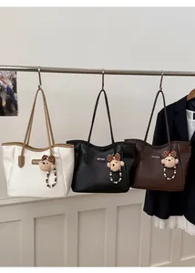 Trois sacs cabas vintage en crème, noir et marron avec breloques d'ours sur crochets