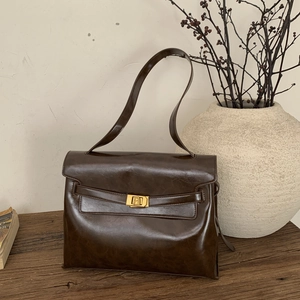 Detail of vintage dark brown tote bag with gold lock buckle on a wooden table