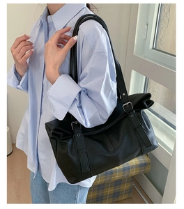 Close-up of black pebble leather tote with adjustable silver buckle and dual shoulder straps