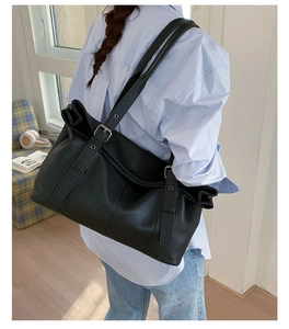 Detail of black large tote bag with lychee texture and metallic adjustment buckle straps