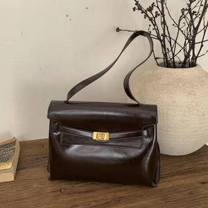 Retro dark brown oily leather shoulder bag with gold clasp shown on a wooden table