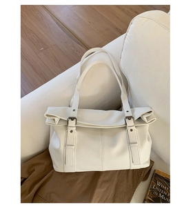 Detailed macro view of white pebble leather texture and metal buckle on tote bag