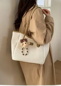 Détail d'un sac cabas blanc avec anses marron et un charmant ours en peluche