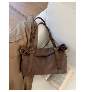 Detailed close-up of brown litchi grain leather tote bag with silver buckle accents