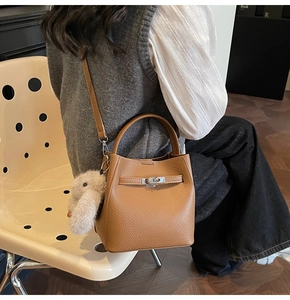 Détail du sac seau en cuir marron avec fermoir rotatif argenté et breloque lapin
