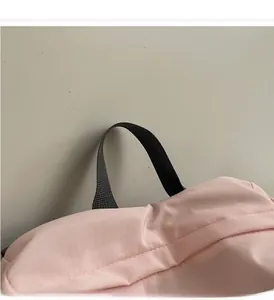 Détail de la poignée renforcée et du tissu en nylon rose résistant sur le sac à dos